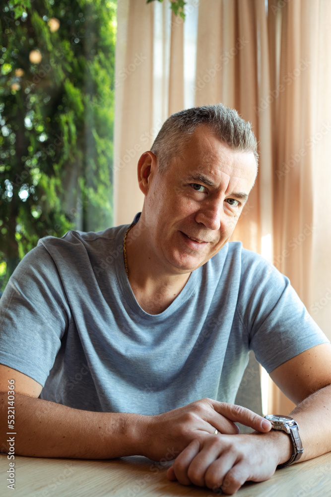 Mature attractive business man sitting with cute smile at table in cafe and watching time on clock. Handsome gray haired 50 years old man resting in cafe. Modern lifestyle, business people Mature attractive business man sitting with cute smile at table in cafe and watching time on clock. Handsome gray haired 50 years old man resting in cafe. Modern lifestyle, business people