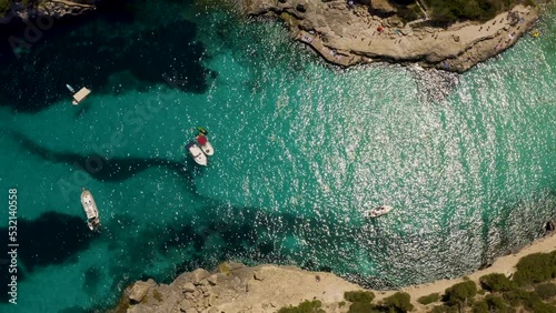 Aerial top down shot in 4k of yacht in crystal clear blue and turquoise Mediterranean Sea in Mallorca, Spain - Luxury Holiday - Balearic Islands