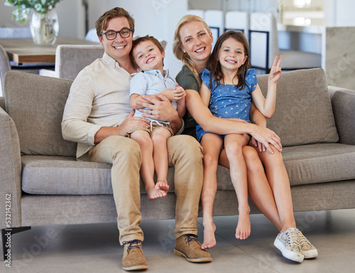 Mother, kids and father in a happy family portrait on sofa in a lovely home and enjoying quality time in the living room. Happiness, smile and young parents with smiling children relaxing together