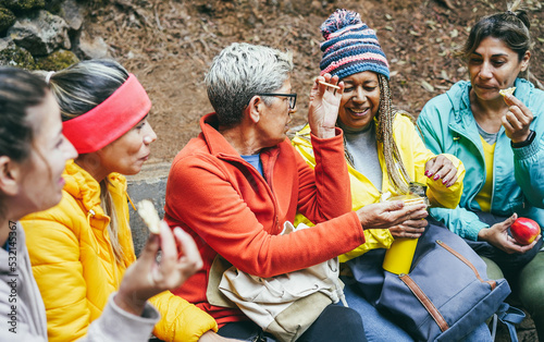 Multiracial women having fun taking a break after trekking day in mountain forest - Focus on center woman face