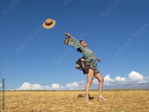 Carefree woman tossing hat in field