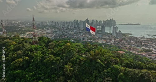 Panama City Aerial v67 cinematic low level flyover ancon hill with wind blowing the national flag on hilltop with coastal downtown cityscape in the background - Shot with Mavic 3 Cine - March 2022 photo