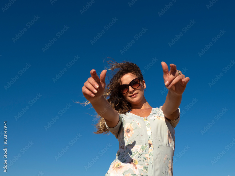 Smiling woman reaching hands at camera in sunlight Smiling woman reaching hands at camera in sunlight