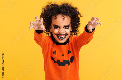 Obraz na płótnie Happy ethnic boy in pumpkin  costume and terrible makeup scary   gestures and ce