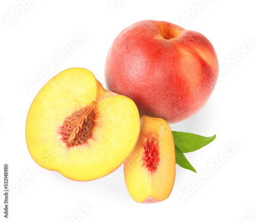 Whole and cut delicious peaches with green leaves isolated on white