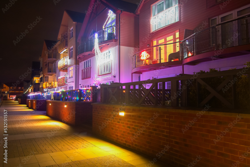Christmas lights, houses decorated for the season in brightly coloured lights. Focus on the balcony's in the foreground. warm glow of the festive lights accentuate the homely feel. copy space.