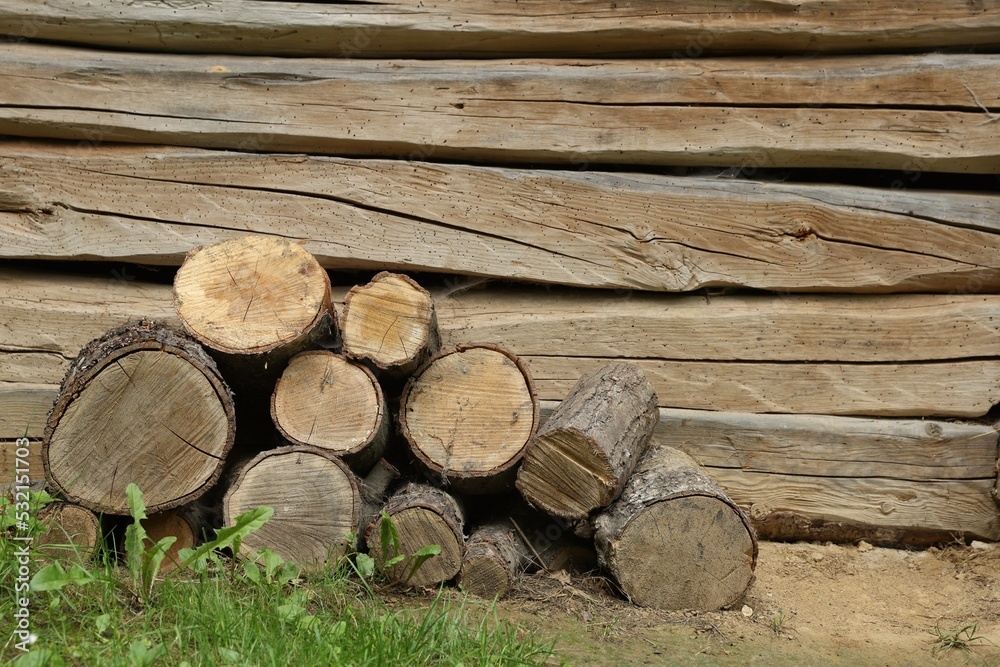 Pile of cut firewood near wooden wall on summer day, space for text Pile of cut firewood near wooden wall on summer day, space for text