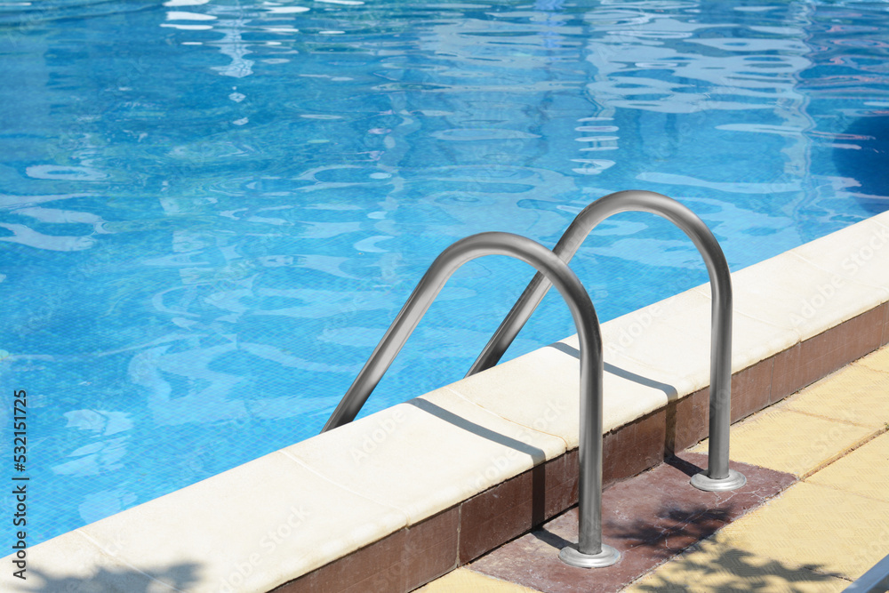 Swimming pool with metal ladder on sunny day