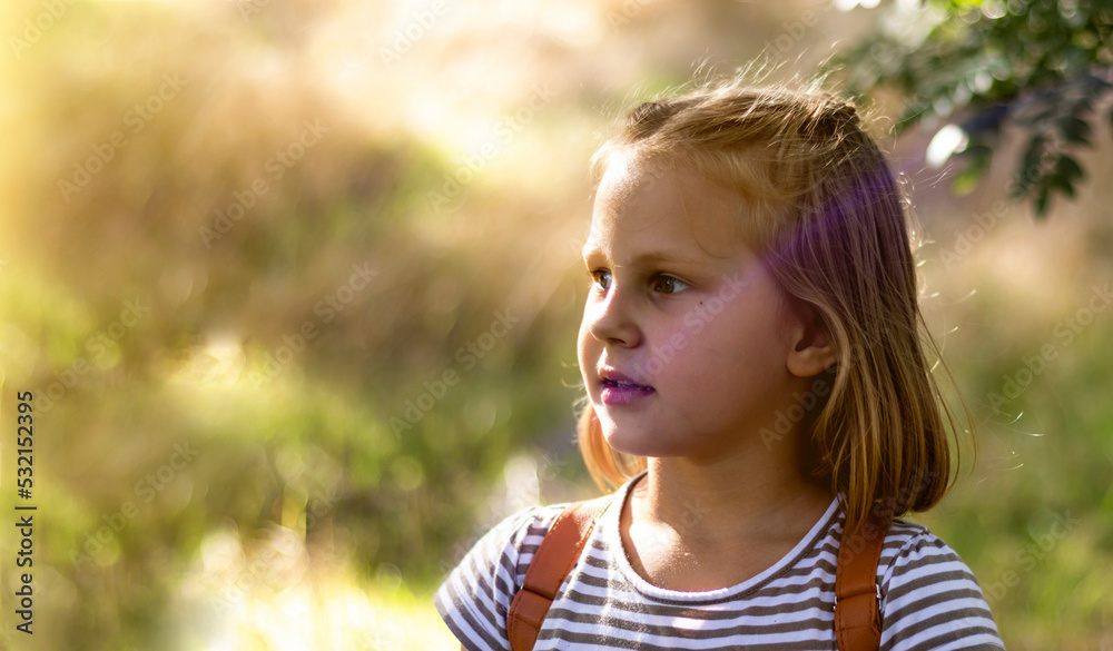 Smiling little girl in the park. Copy space. Happy child looking away. Portrait of a laughing kid outside. Banner. Smiling little girl in the park. Copy space. Happy child looking away. Portrait of a laughing kid outside. Banner.