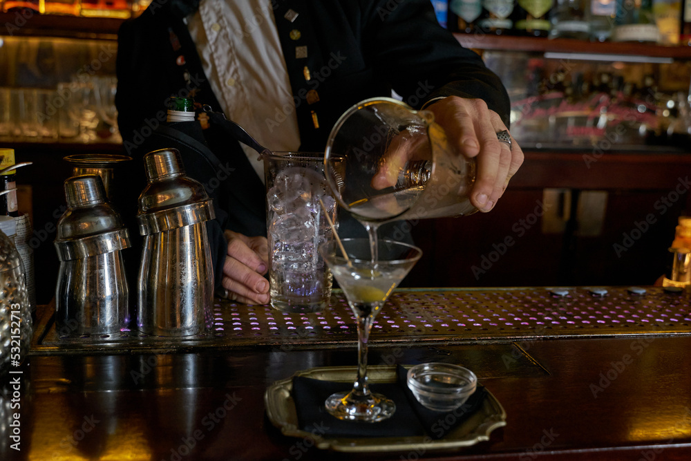 Bartender preparing a dry martini at an authentic wooden bar counter 