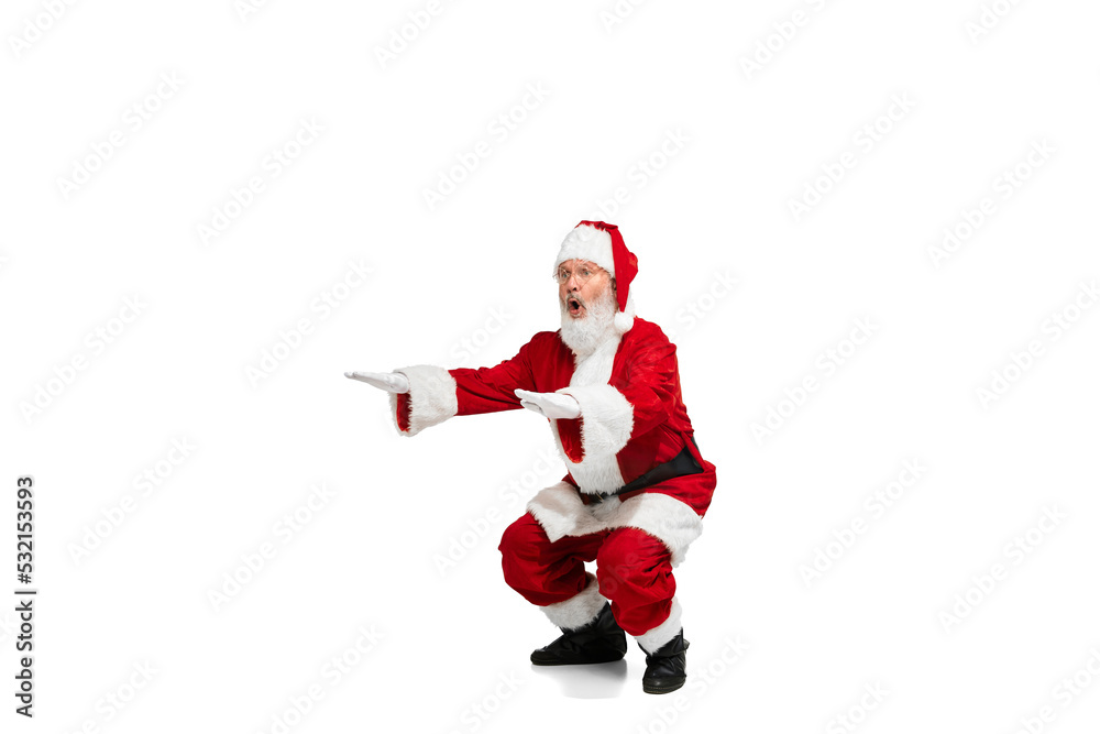 Portrait of senior man in image of Santa Claus training, doing squats isolated over white background Portrait of senior man in image of Santa Claus training, doing squats isolated over white background