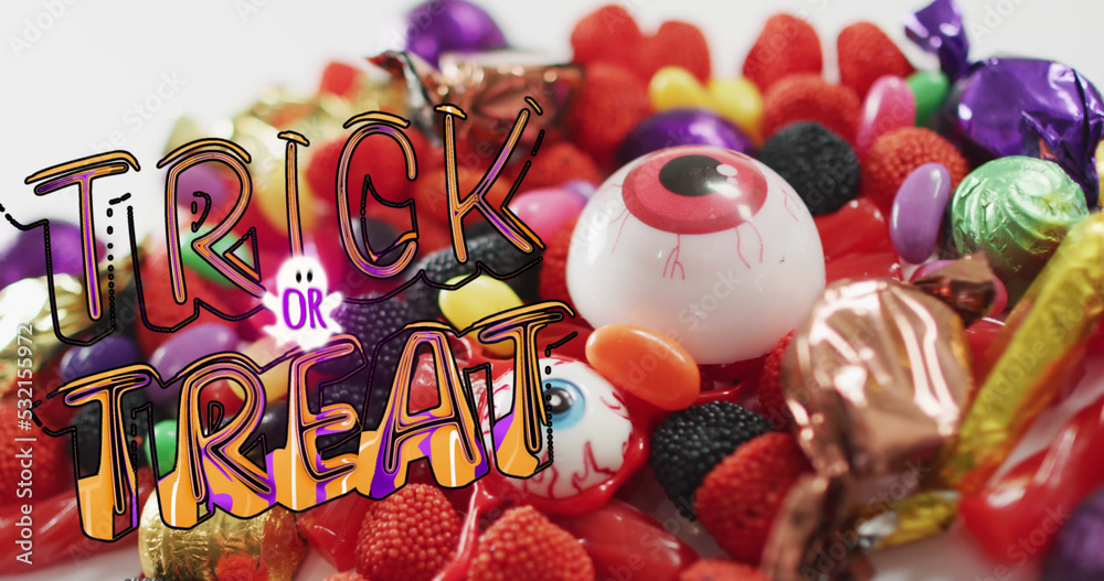 Naklejka premium Image of halloween trick or treat text over sweets on grey background