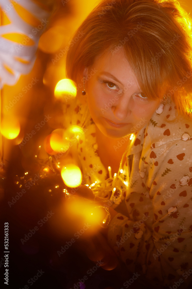 Happy adult middle aged woman wearing pajamas in room with Christmas decorations. New Year holiday in Russia