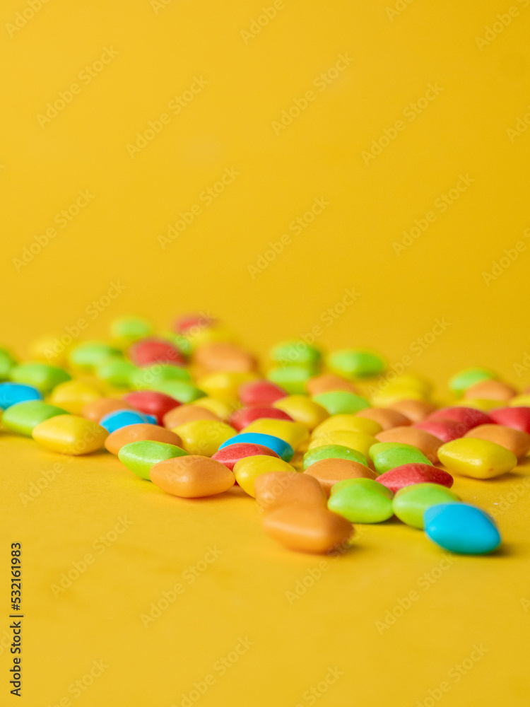 Multicolored marmalade sweets on a yellow background. Place for text