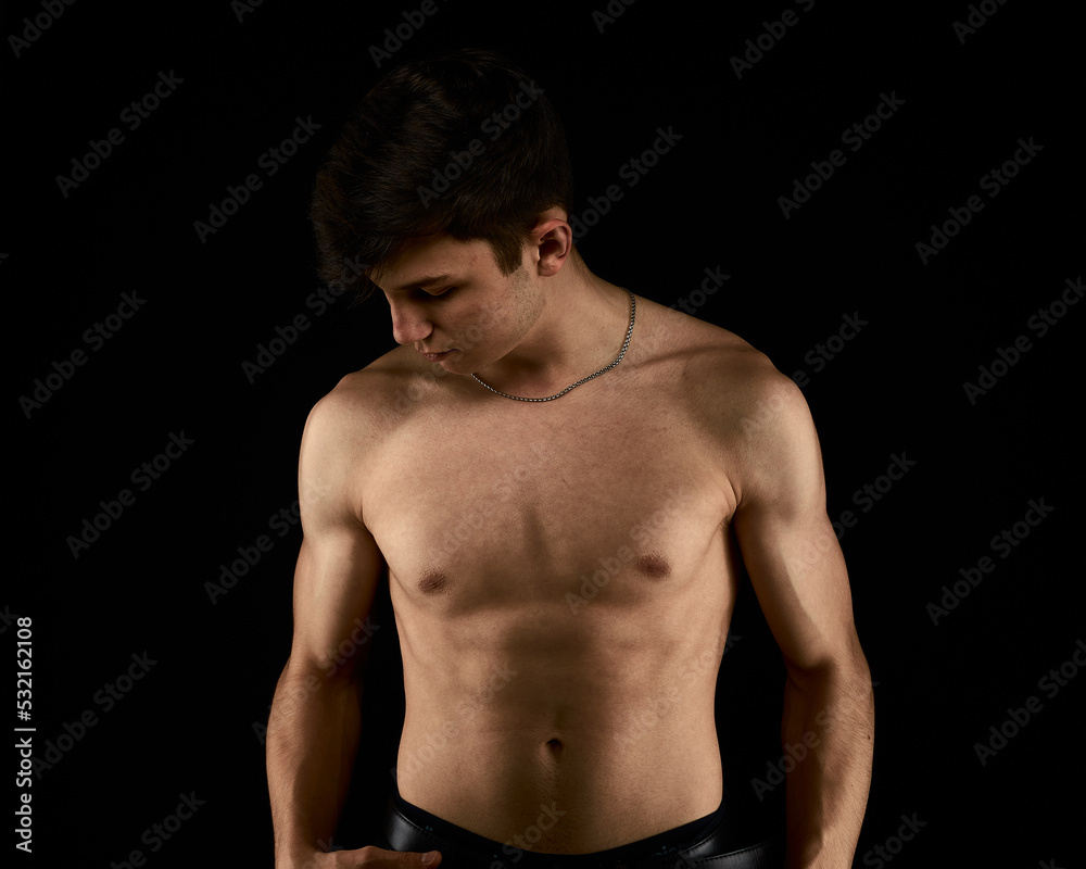 a healthy athletic teenager shows off his body against a dark background, the concept of proper nutrition a healthy athletic teenager shows off his body against a dark background, the concept of proper nutrition