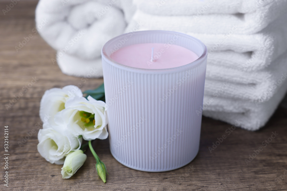 Scented candle, folded towels and eustoma flowers on wooden table Scented candle, folded towels and eustoma flowers on wooden table