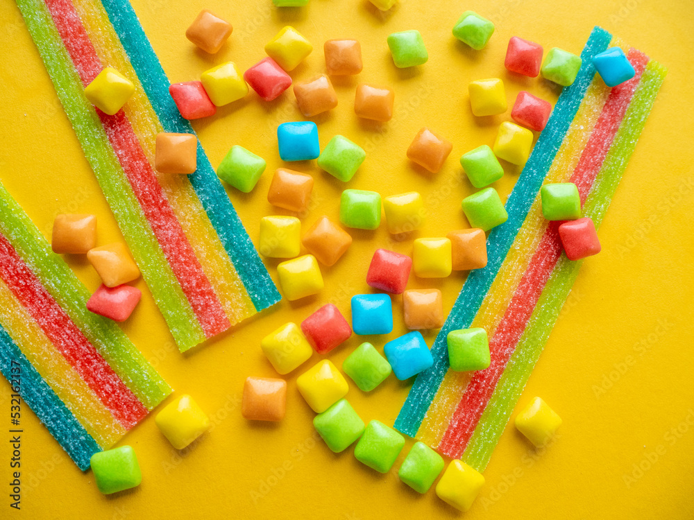 Multicolored marmalade sweets on a yellow background.