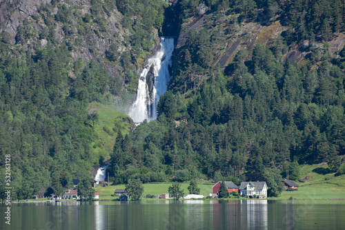 Wonderful landscapes in Norway. Vestland. Beautiful scenery of  Glomnesfossen waterfall and Oppstrynsvatn lake in Hjelle. Mountain, rocks and trees in background. Summer sunny day. Selective focus photo