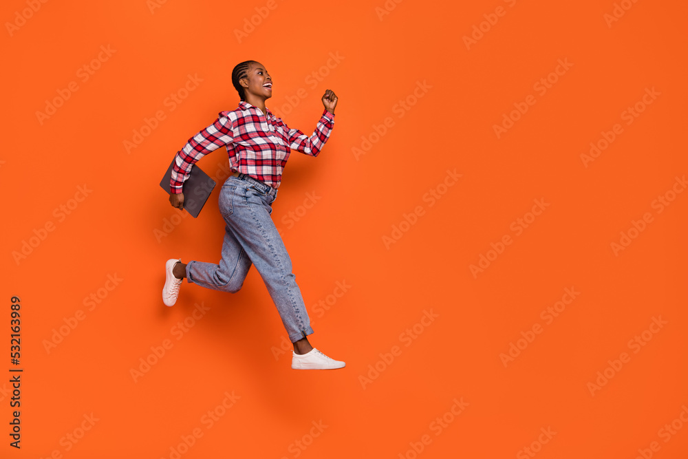 Full body profile photo of energetic pretty girl hurry jumping look empty space isolated on orange color background