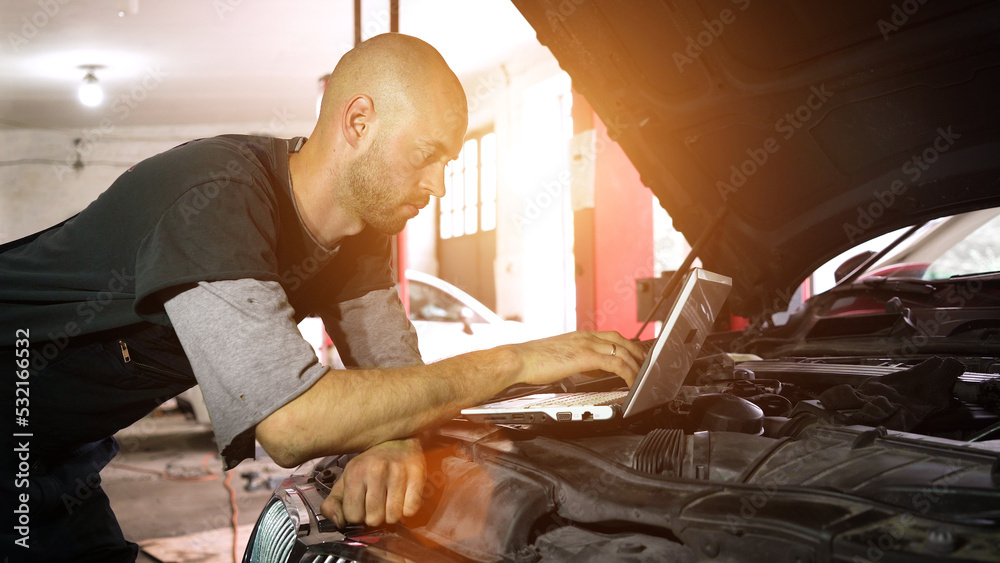 Fototapeta premium auto repairman diagnoses a car using a computer. car workshop. close-up