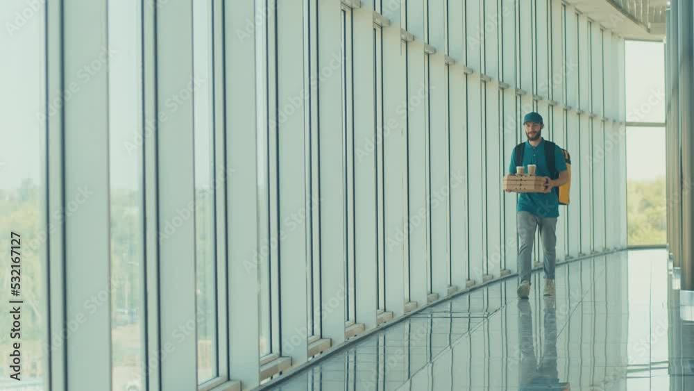 Handsome Delivery Man With Thermal Backpack Brings Pizza Boxes, Coffee to Modern Office Building. Deliveryman Worker Deliver Online Order Client. Courier on the Way to Deliver Order to a Client Handsome Delivery Man With Thermal Backpack Brings Pizza Boxes, Coffee to Modern Office Building. Deliveryman Worker Deliver Online Order Client. Courier on the Way to Deliver Order to a Client