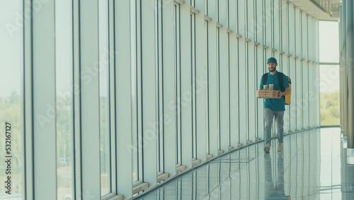 Wallpaper Mural Handsome Delivery Man With Thermal Backpack Brings Pizza Boxes, Coffee to Modern Office Building. Deliveryman Worker Deliver Online Order Client. Courier on the Way to Deliver Order to a Client Torontodigital.ca