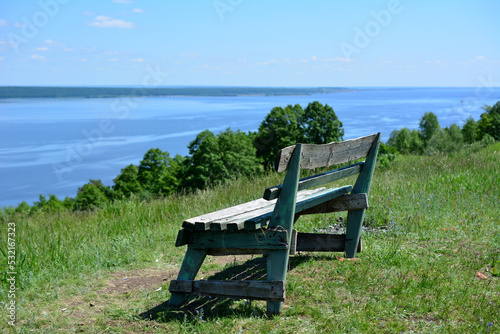 wooden bench on the edge of the mountain with view to the river