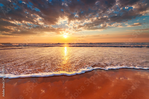 Fototapeta Naklejka Na Ścianę i Meble -  Beautiful sunrise with dramatic cloudscape over the sea waves and beach