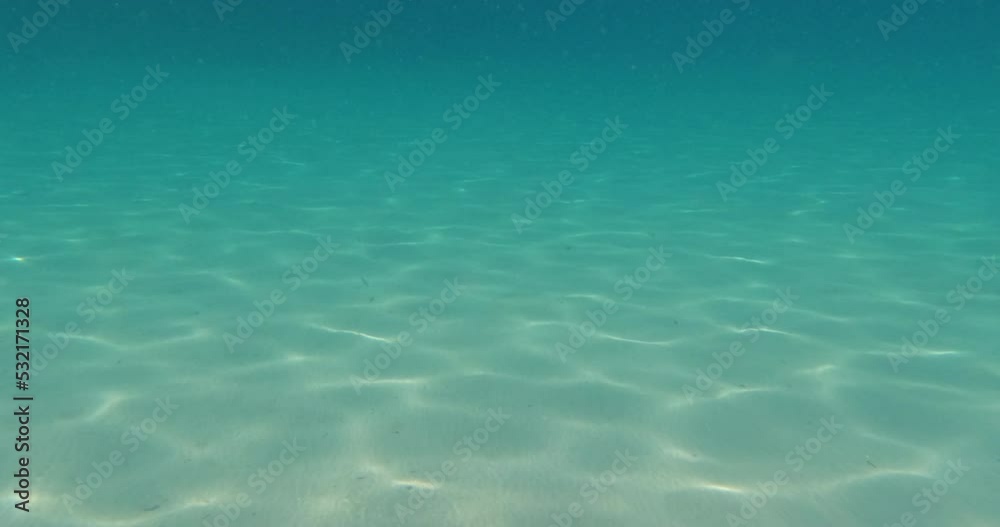 Underwater footage scene of moving through turquoise color sea water. Ripple sunlight rays on sea bottom. Beautiful under water surface seascape at Aegean sea. 4K video slow motion.	