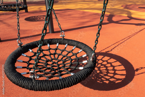 Black rope swings at children playground in summer season. Empty seat
