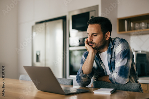 A man getting tired of work, using a laptop, working online, at home.