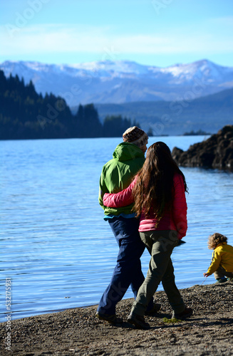 couple walking along the shore of a lake and child playing © Lautaro