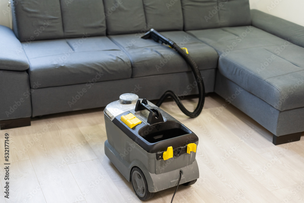 Closeup Of Woman Cleaning Sofa With Vacuum Cleaner At Home