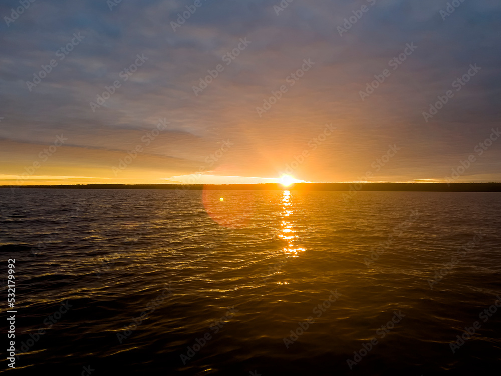 Water surface. View of a Sunset sky background. Dramatic gold sunset sky with evening sky clouds over the lake. Clear water texture. Landscape. Water reflection