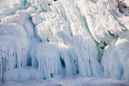 Rocks in icicles of ice. Winter journey on the ice of the frozen Lake Baikal.