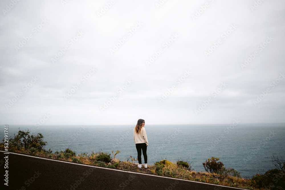 Woman standing on road near the sea Woman standing on road near the sea