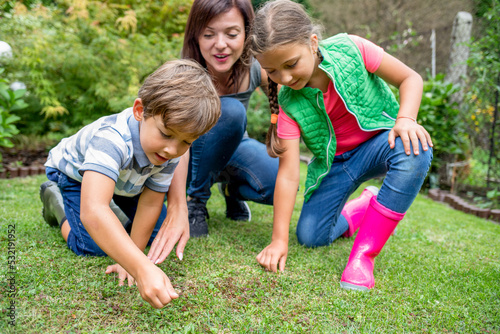 Mom with her children seeding grass in their family garden