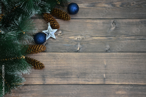 pine branches with cones and christmas spheres on wooden background