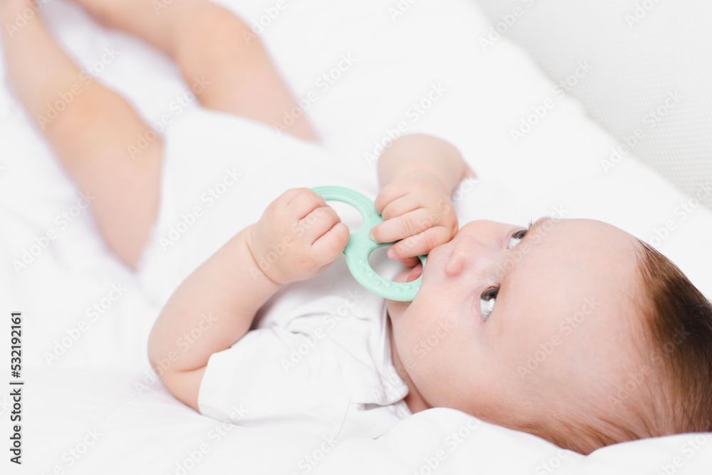 A baby with a teether on a white background . Teething. Children's article. A baby with a teether on a white background . Teething. Children's article.
