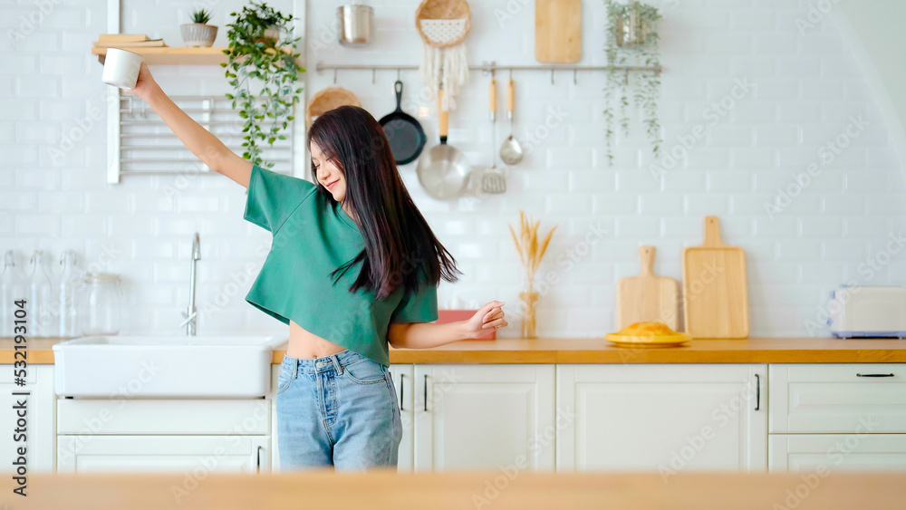 Asian young woman dancing in kitchen room. Female happy and relaxing at free time on weekend Asian young woman dancing in kitchen room. Female happy and relaxing at free time on weekend