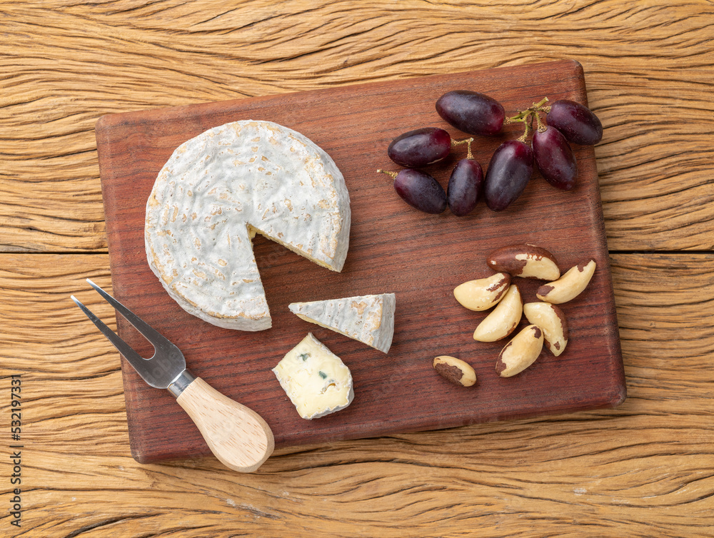 Brazilian artisan Bofete blue cheese with nuts and fruits over wooden table Brazilian artisan Bofete blue cheese with nuts and fruits over wooden table
