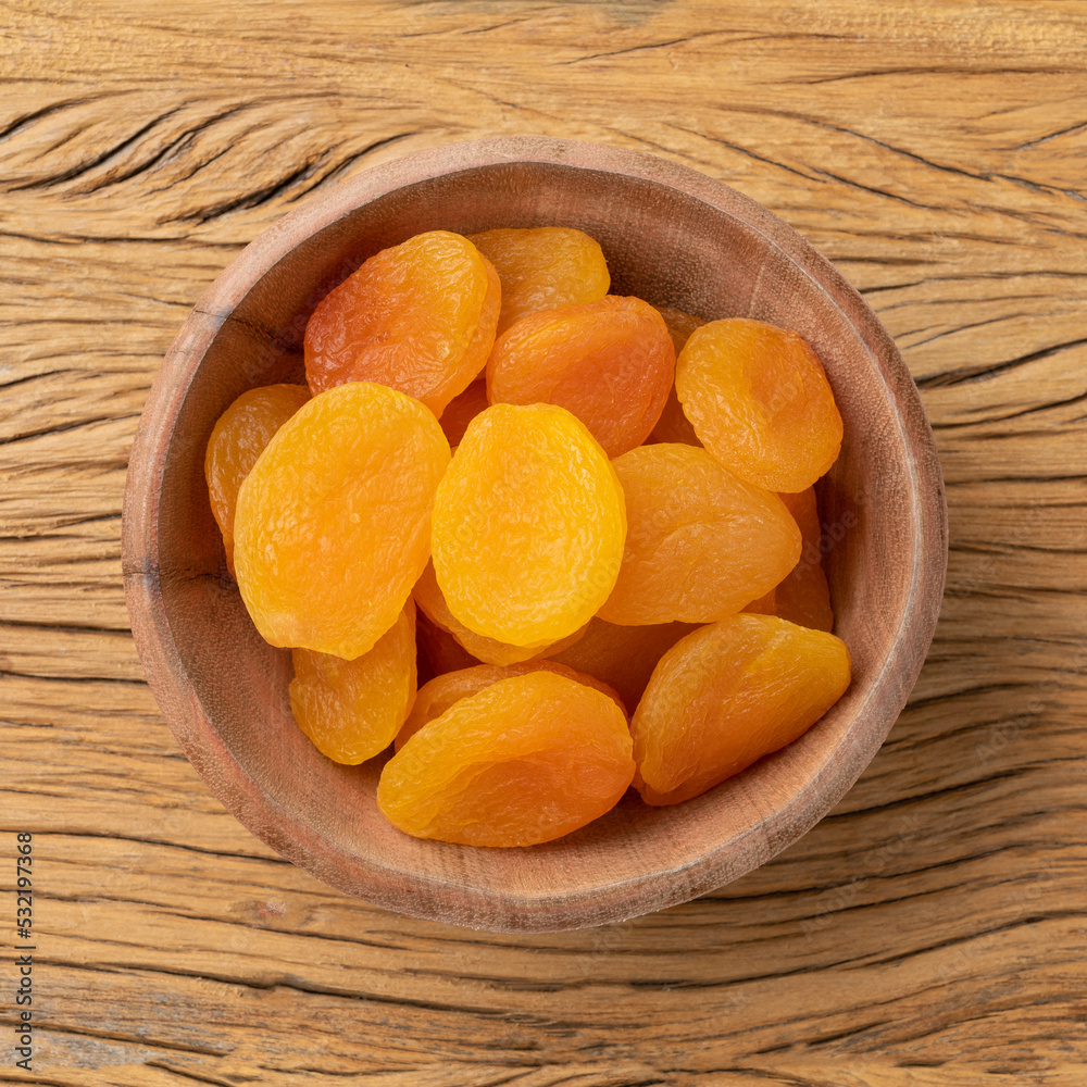 Dried apricots in a bowl over wooden table Dried apricots in a bowl over wooden table
