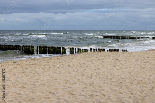 Seaside landscape  foamy water of the Baltic Sea with a wooden breakwater. Cloudy sky  Island Wolin  Miedzyzdroje  Poland