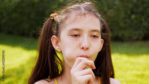 Close-up of an 8-year-old girl eating a lollipop in close-up.