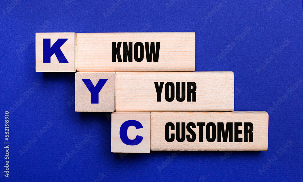 On a bright blue background, light wooden blocks and cubes with the text KYC KNOW YOUR CUSTOMER