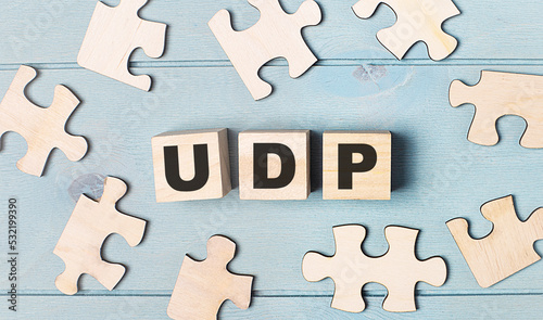 Blank puzzles and wooden cubes with the text UDP User Datagram Protocol lie on a light blue background.
