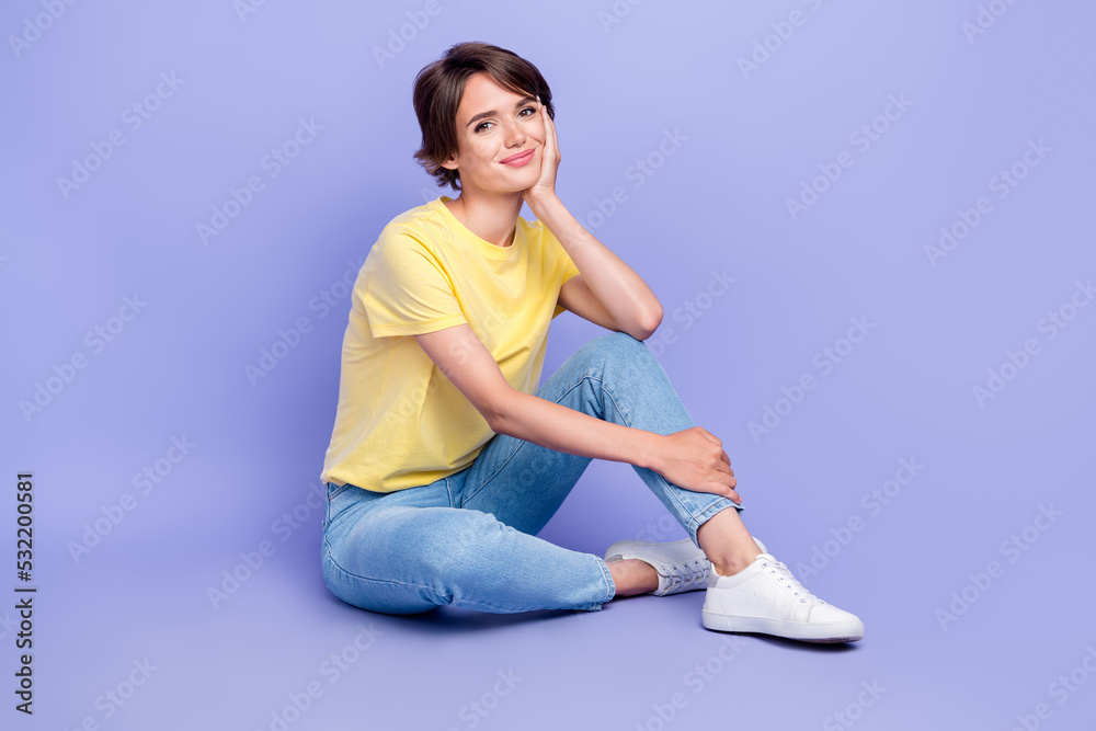 Full body photo of gorgeous satisfied lady sit floor hand touch cheek isolated on violet color background Full body photo of gorgeous satisfied lady sit floor hand touch cheek isolated on violet color background