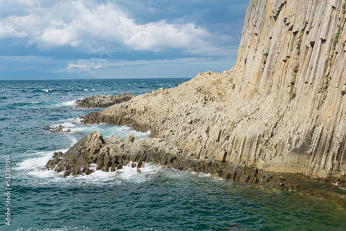 rocky seashore formed by columnar basalt against the backdrop of a sea, coastal landscape of the Kuril Islands © Evgeny