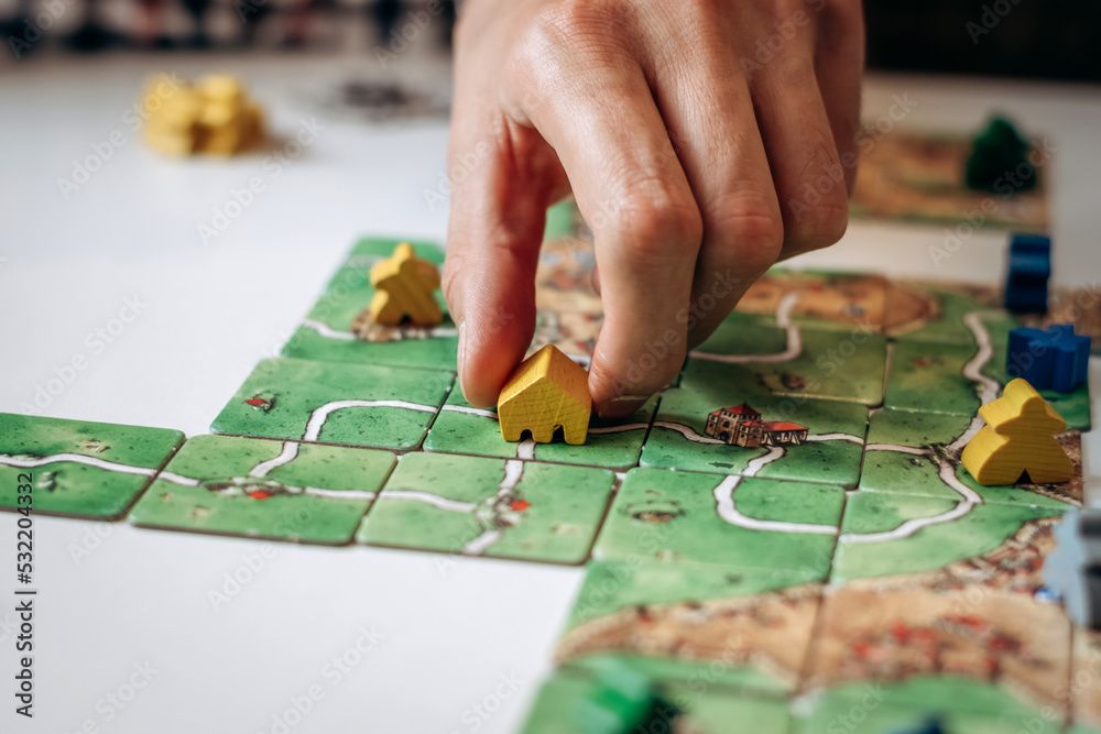 Fototapeta premium A group of young people play board games at home in the kitchen.Hands close-up.Time together.Stay home,board games concept.Selective focus.
