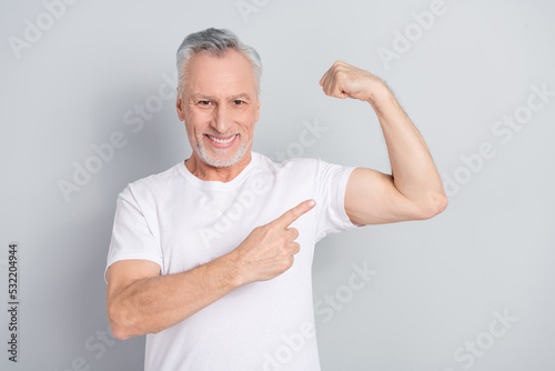 Photo of cool elder man index biceps wear white t-shirt isolated on grey color background